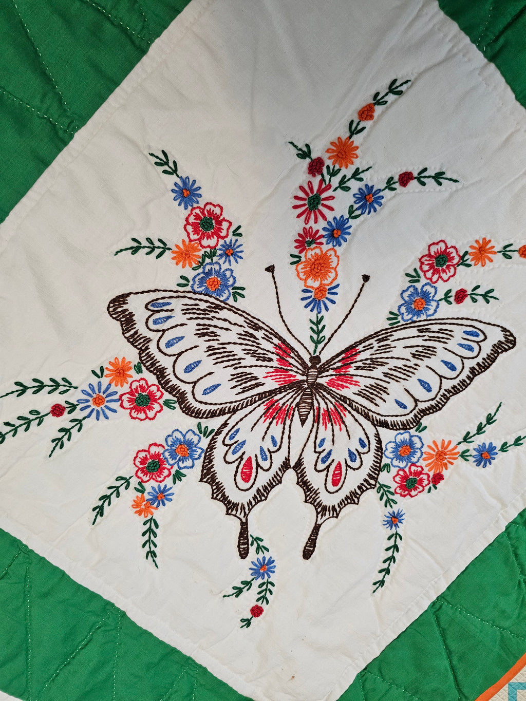 Vintage handmade patchwork quilt featuring a 3x4 grid of embroidered butterfly and floral motif blocks,