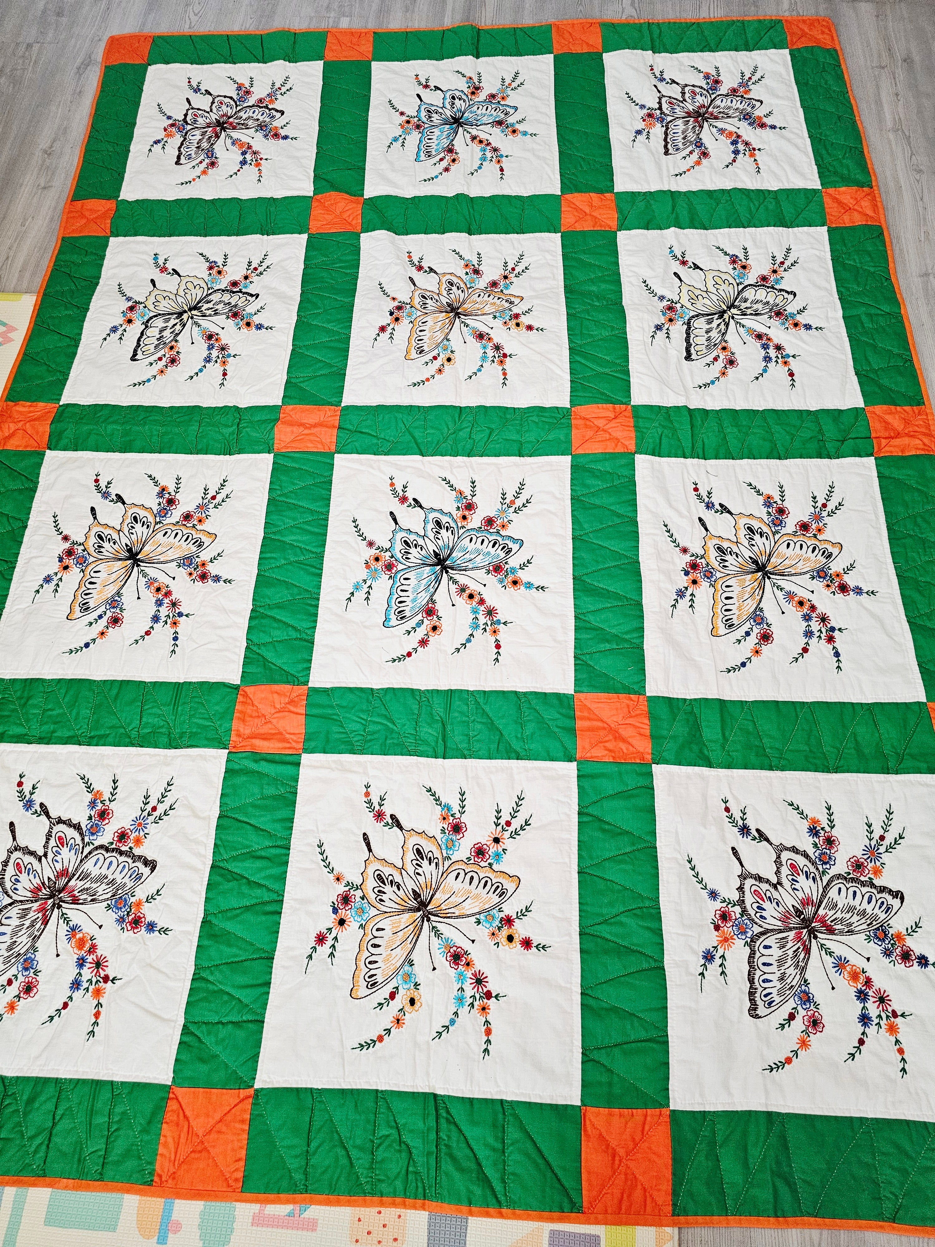 Vintage handmade patchwork quilt featuring a 3x4 grid of embroidered butterfly and floral motif blocks,