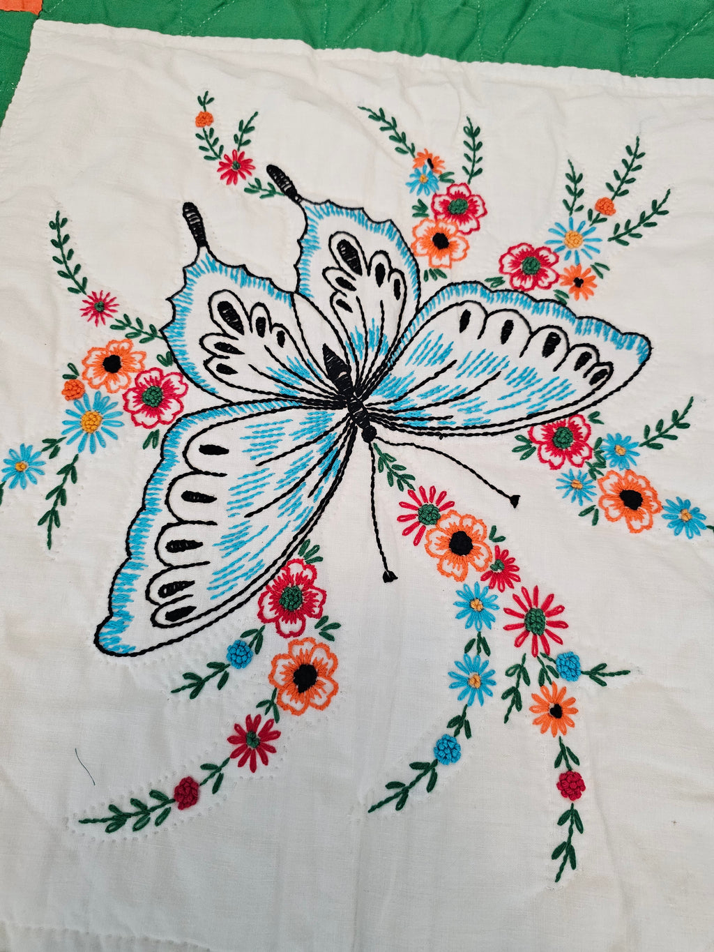 Vintage handmade patchwork quilt featuring a 3x4 grid of embroidered butterfly and floral motif blocks,
