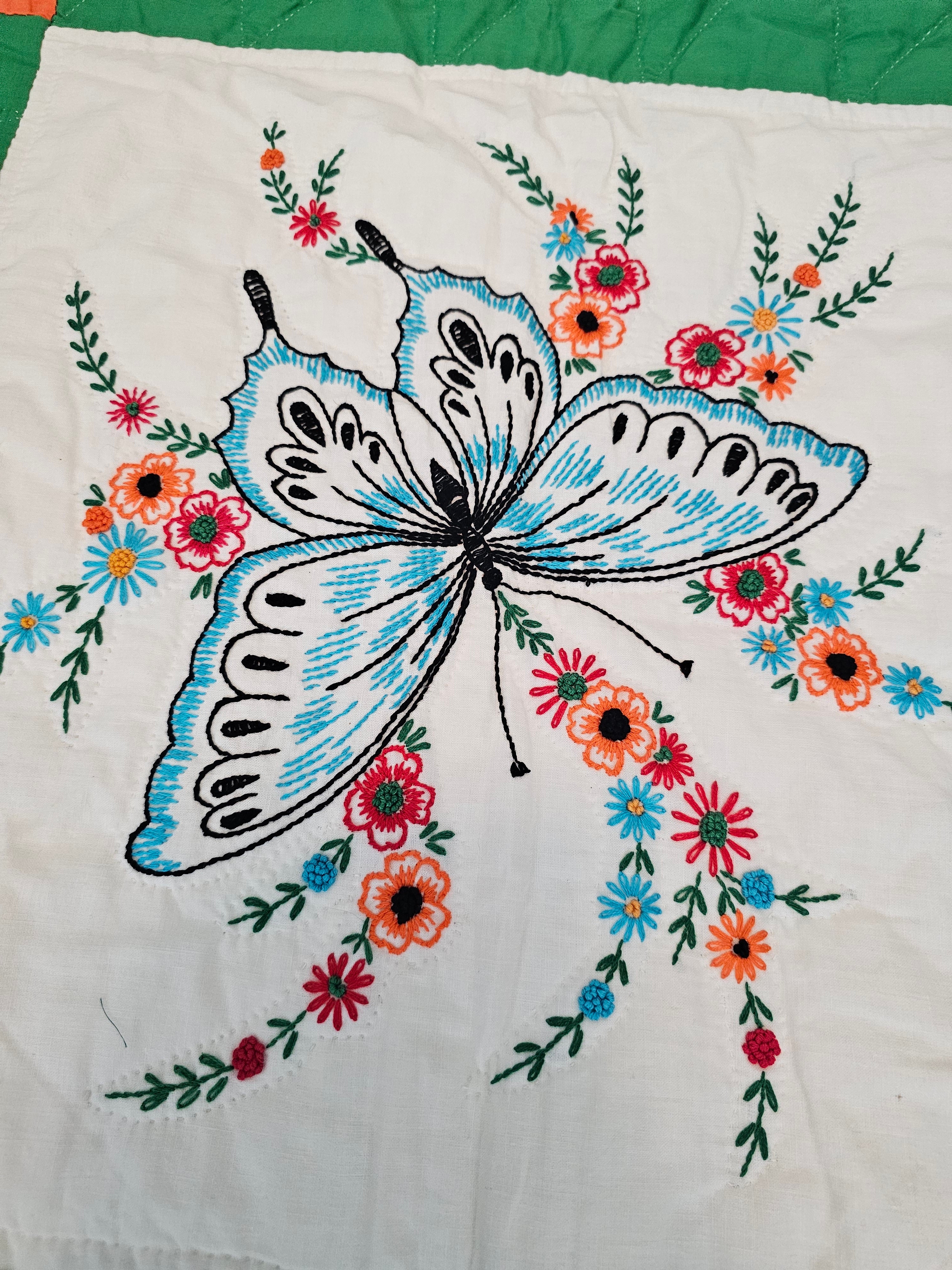 Vintage handmade patchwork quilt featuring a 3x4 grid of embroidered butterfly and floral motif blocks,
