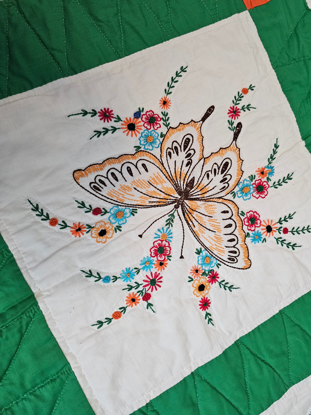 Vintage handmade patchwork quilt featuring a 3x4 grid of embroidered butterfly and floral motif blocks,