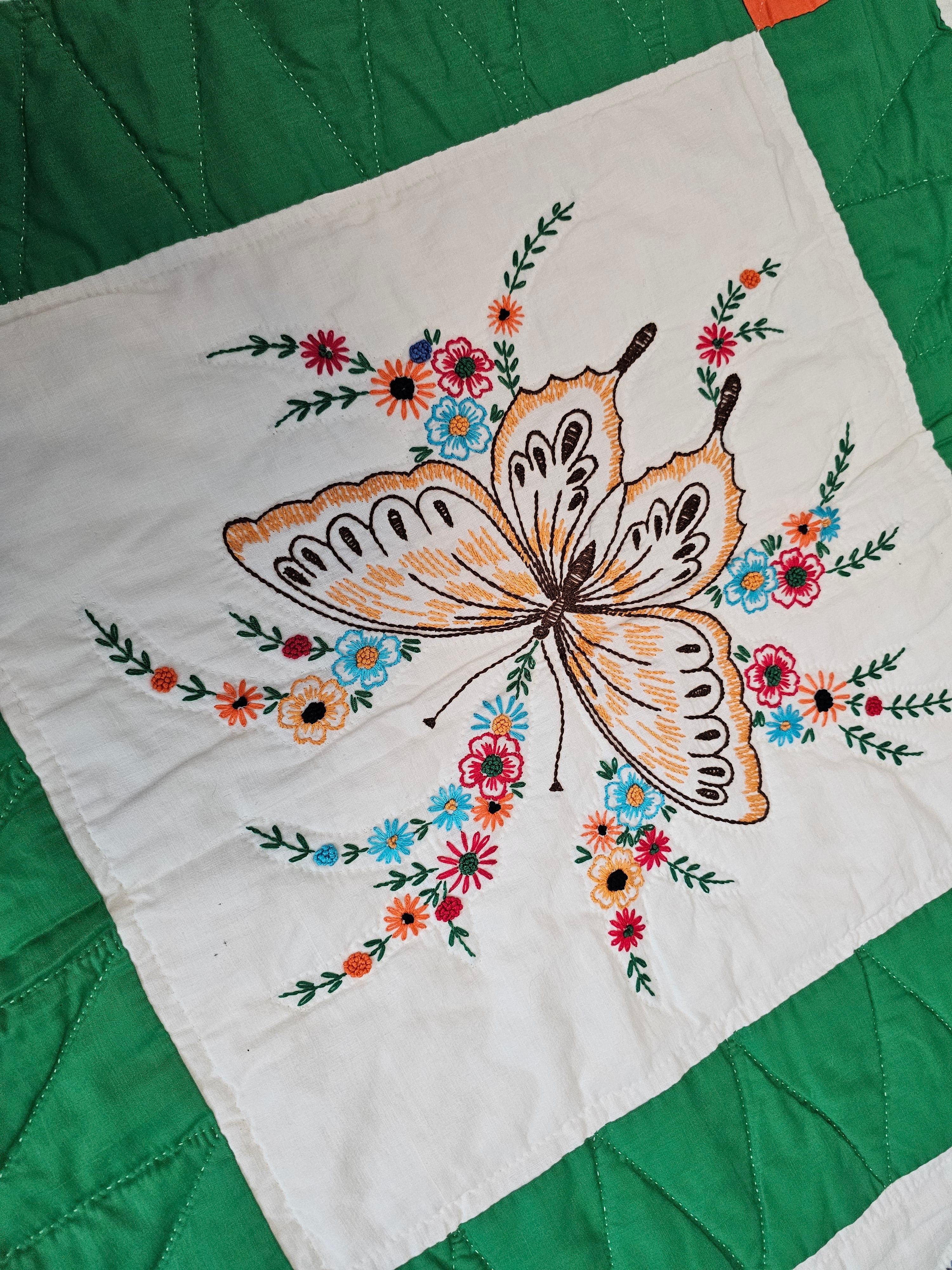 Vintage handmade patchwork quilt featuring a 3x4 grid of embroidered butterfly and floral motif blocks,